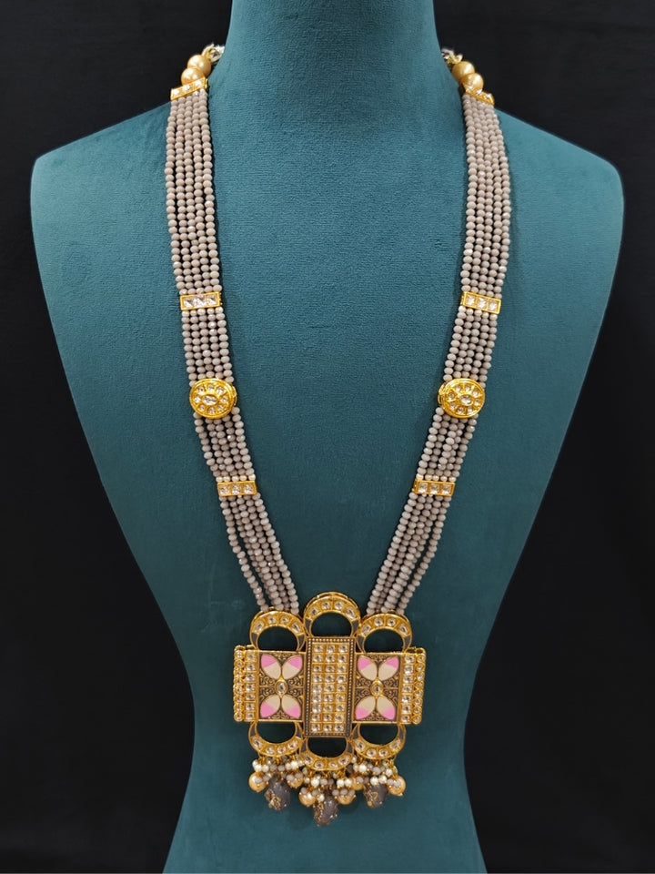 Close-up of an ornate traditional Grey Rajwadi and Meenakari gold Long jewellery set and earrings  with Kundan, Meenakari work, crystal beads and pearls.  A royal Rajwadi and Meenakari artificial necklace set for a traditional Indian wedding. Luxury imitation Rajwadi and Meenakari necklace worn for wedding celebrations.