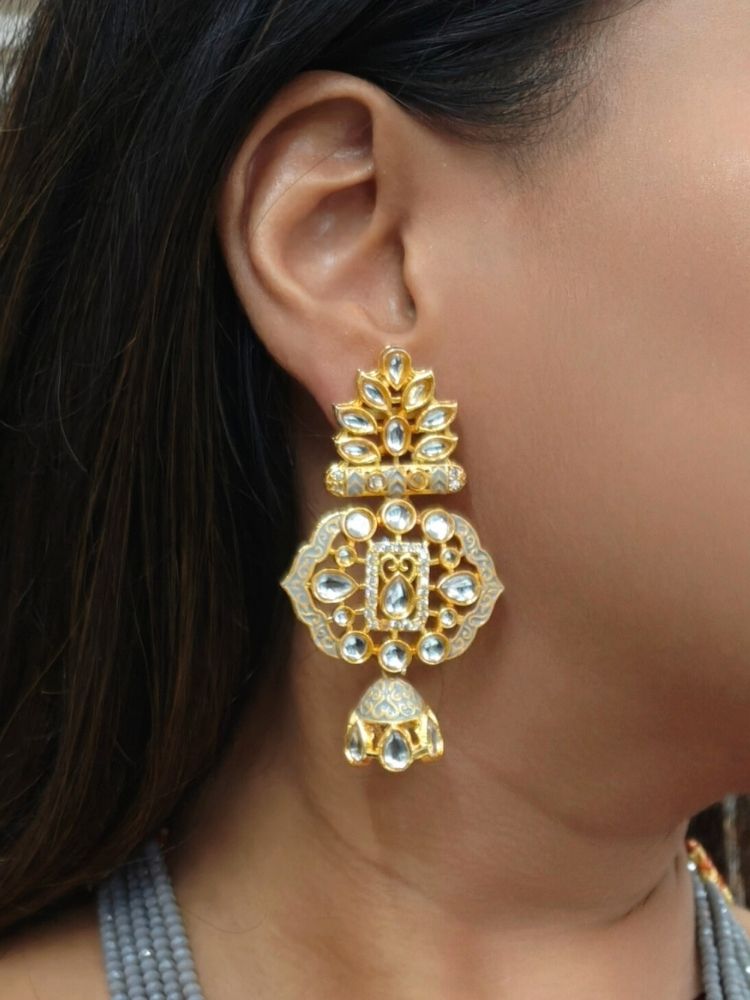 A woman in a traditional red, gold, and green silk saree wears the Grey Shazia Necklace Set with matching earrings and poses in profile with a smile—an elegant choice for a wedding ceremony. Kundan Meenakari pendant hanging with grey crystal stones, and pearls, perfect for weddings. 