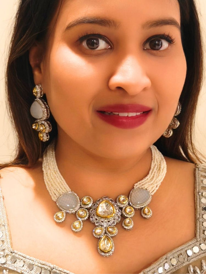 A woman in a Gold embroidered outfit smiles, showcasing the Peacoski GreyTamanna Necklace Set and matching earrings. Her soft makeup highlights the elegance of this statement jewelry ensemble.