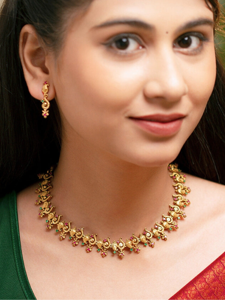 Close-up of a woman wearing an ornate traditional (Gold Polish) Collar jewellery set and earrings with Colored Stone and American Diamond. Mehendi ceremony look completed with a Colored Stone jewelry set. Festive Diwali outfit paired with a colorful Colored Stone necklace.