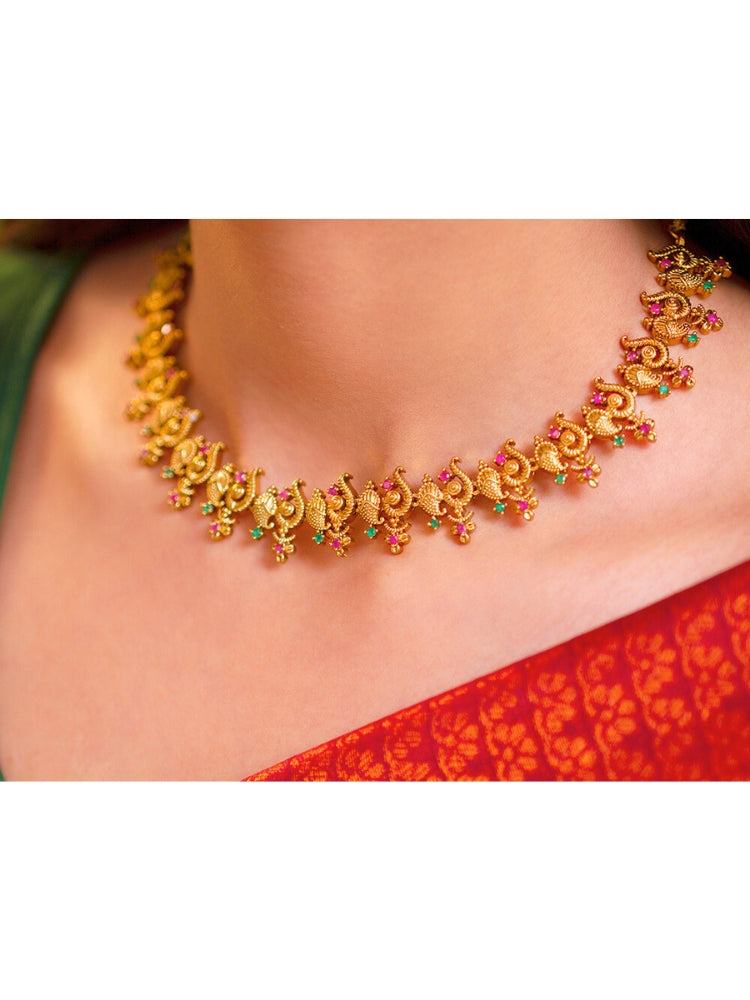 Close-up of a woman wearing an ornate traditional (Gold Polish) Collar jewellery set and earrings with Colored Stone and American Diamond. Mehendi ceremony look completed with a Colored Stone jewelry set. Festive Diwali outfit paired with a colorful Colored Stone necklace.