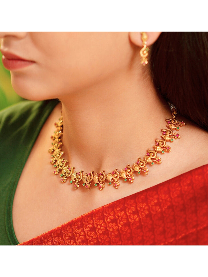 Close-up of a woman wearing an ornate traditional (Gold Polish) Collar jewellery set and earrings with Colored Stone and American Diamond. Mehendi ceremony look completed with a Colored Stone jewelry set. Festive Diwali outfit paired with a colorful Colored Stone necklace.