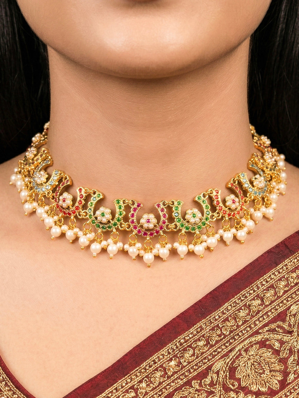 Close-up of a woman wearing an ornate traditional Navratan jadau gold jewellery set and jadau earrings with navratan color stone and Pearls. Woman wearing a premium Jadau artificial jewelry set for reception night. Mehendi function outfit styled with a lightweight Jadau necklace.
