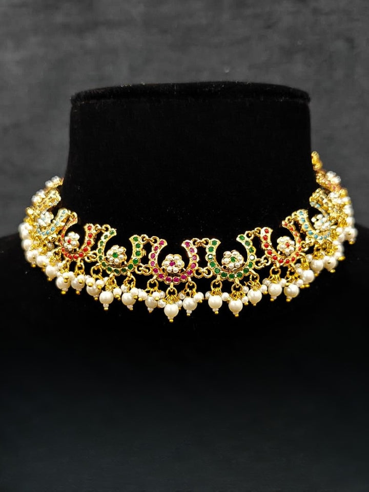 Close-up of an ornate traditional Navratan jadau gold jewellery set and jadau earrings with navratan color stone and Pearls. Festive celebration look featuring a Jadau artificial necklace. Elegant look featuring a luxury Jadau artificial jewelry set.