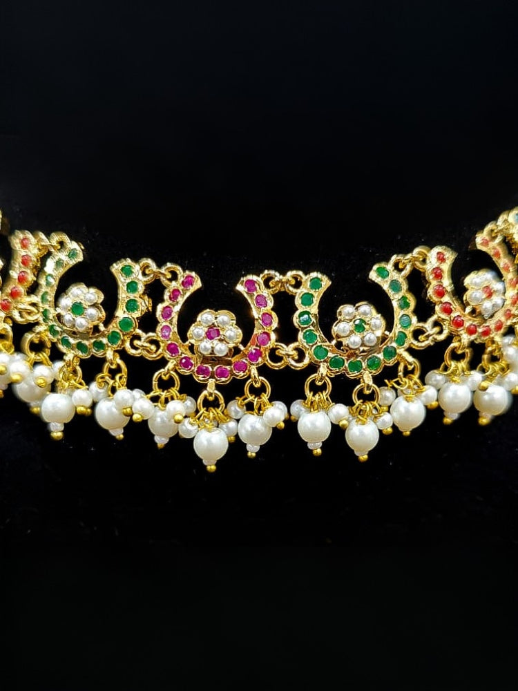 Close-up of an ornate traditional Navratan jadau gold jewellery set and jadau earrings with navratan color stone and Pearls. Festive celebration look featuring a Jadau artificial necklace. Elegant look featuring a luxury Jadau artificial jewelry set.