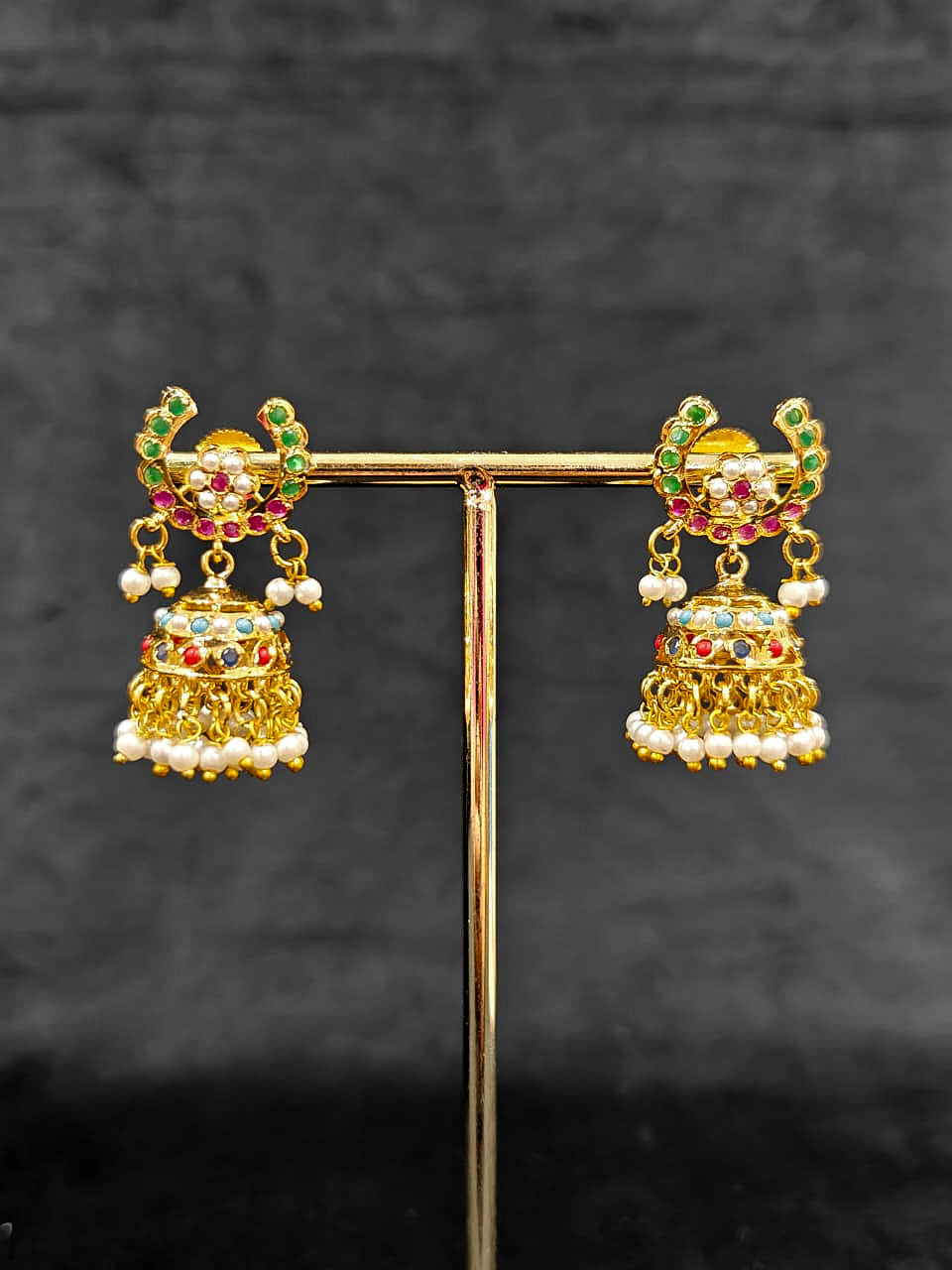 Close-up of an ornate traditional Navratan jadau gold jewellery set and jadau earrings with navratan color stone and Pearls. Festive celebration look featuring a Jadau artificial necklace. Elegant look featuring a luxury Jadau artificial jewelry set.