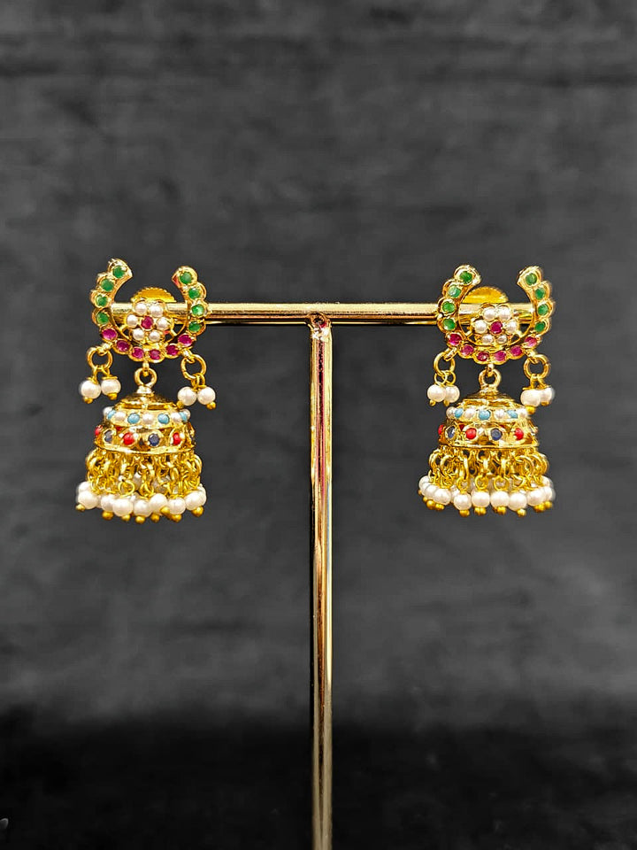 Close-up of an ornate traditional Navratan jadau gold jewellery set and jadau earrings with navratan color stone and Pearls. Festive celebration look featuring a Jadau artificial necklace. Elegant look featuring a luxury Jadau artificial jewelry set.