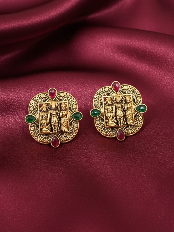 The Hari Earrings featuring a traditional gold Stud Earrings with Goddess Ram, Laxman, and sita in the middle, along with red & Green color stone. Festive Diwali look completed with a traditional temple Stud Earrings.