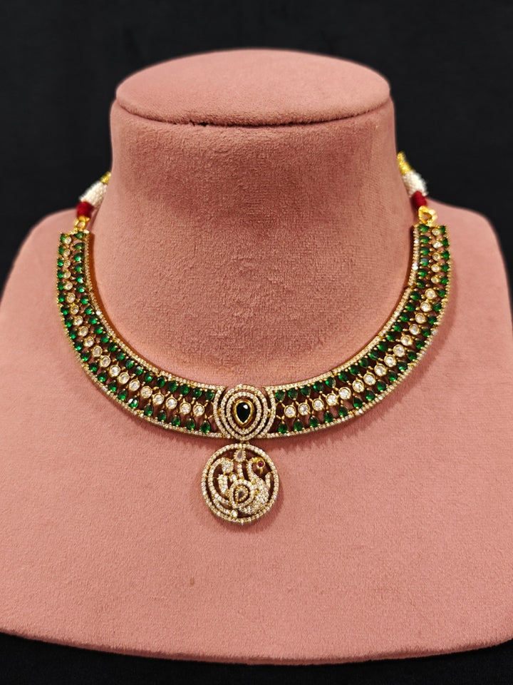 A gorgeous artificial diamond and green colored stone  necklace paired with diamond earrings. This artificial diamond jewelry set offers a traditional yet modern touch for Indian brides, designed to add elegance and sophistication to any occasion.