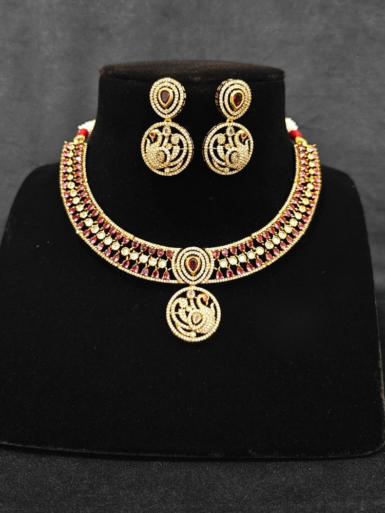 A gorgeous artificial diamond and Red colored stone necklace paired with diamond earrings. This artificial diamond jewelry set offers a traditional yet modern touch for Indian brides, designed to add elegance and sophistication to any occasion.