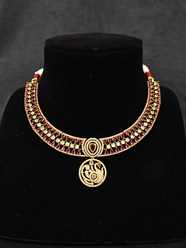 A gorgeous artificial diamond and Red colored stone necklace paired with diamond earrings. This artificial diamond jewelry set offers a traditional yet modern touch for Indian brides, designed to add elegance and sophistication to any occasion.
