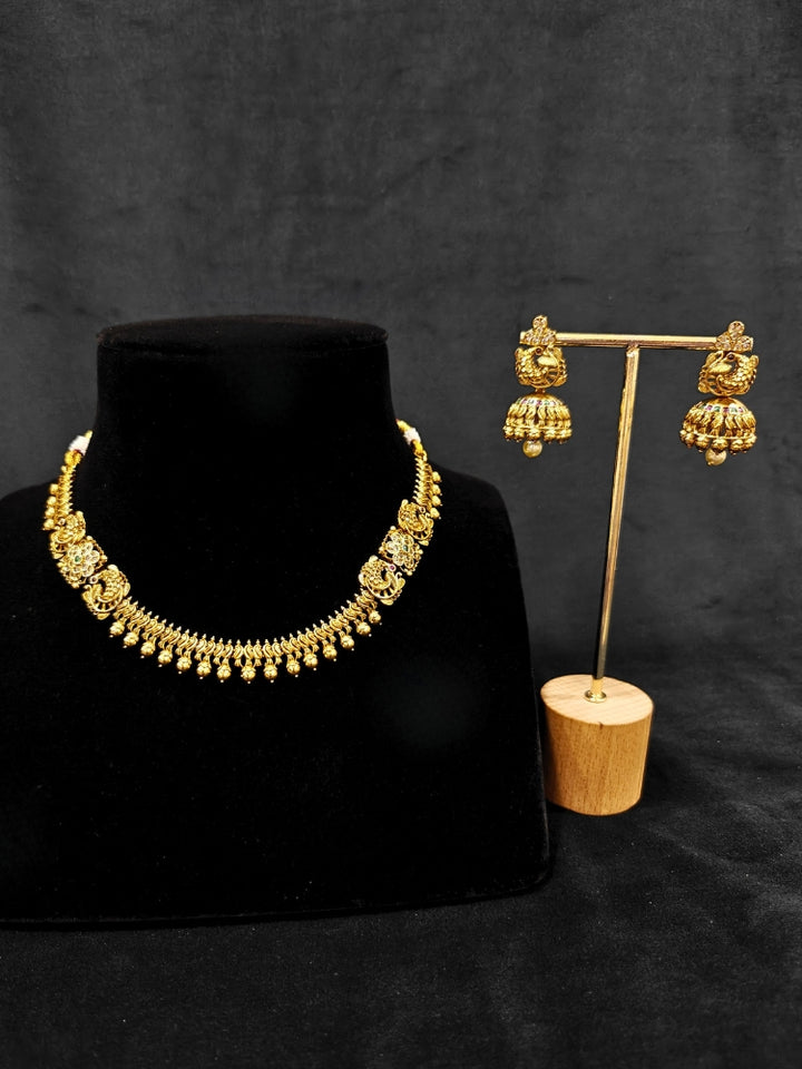 Close-up of an ornate traditional (Gold Polish) Collar jewellery set and earrings with Colored Stones. Festive Diwali outfit paired with a colorful Colored Stone necklace. Mehendi ceremony look completed with a Colored Stone jewelry set.