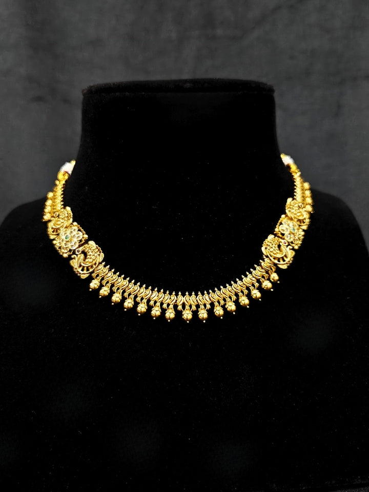 Close-up of an ornate traditional (Gold Polish) Collar jewellery set and earrings with Colored Stones. Festive Diwali outfit paired with a colorful Colored Stone necklace. Mehendi ceremony look completed with a Colored Stone jewelry set.