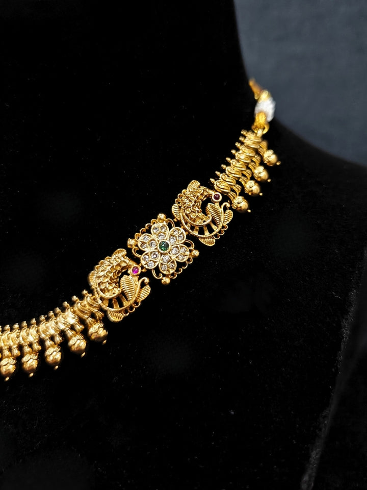 Close-up of an ornate traditional (Gold Polish) Collar jewellery set and earrings with Colored Stones. Festive Diwali outfit paired with a colorful Colored Stone necklace. Mehendi ceremony look completed with a Colored Stone jewelry set.