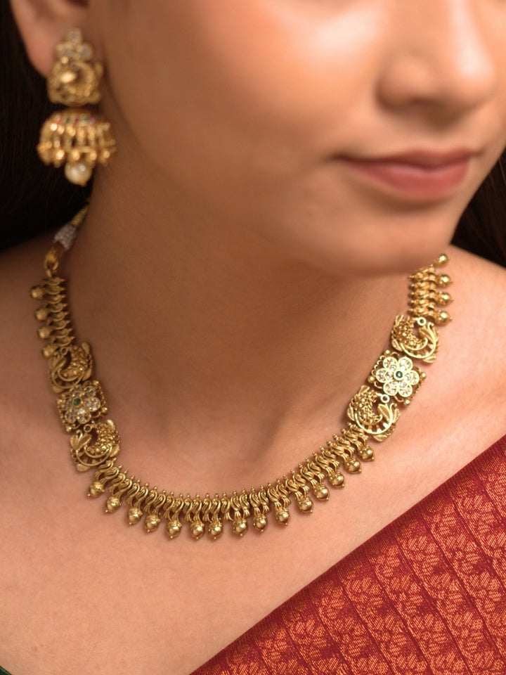 Close-up of a Women Wearing an ornate traditional (Gold Polish) Collar jewellery set and earrings with Colored Stones. Festive Diwali outfit paired with a colorful Colored Stone necklace. Mehendi ceremony look completed with a Colored Stone jewelry set.