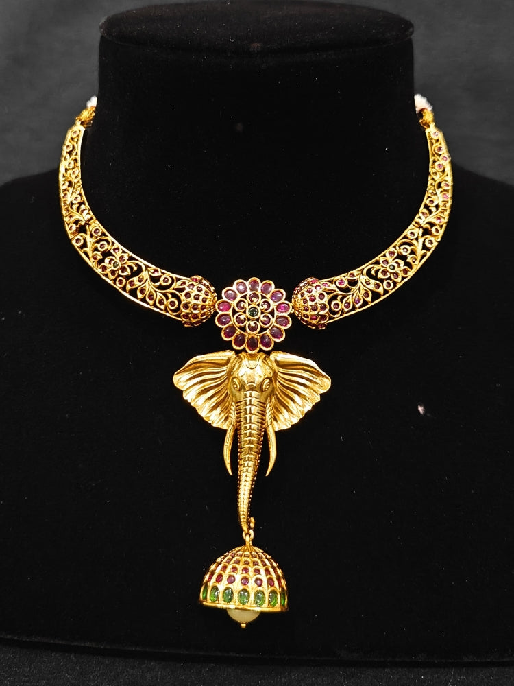 The Hastika Hasli Necklace Set featuring a traditional gold Collar hasli necklace and matching earrings with Goddess Ganesh in the middle, along with pink and green colored stones and golden elephants. Ideal party jewelry for any festive occasion. Festive Diwali look completed with a traditional temple necklace set.