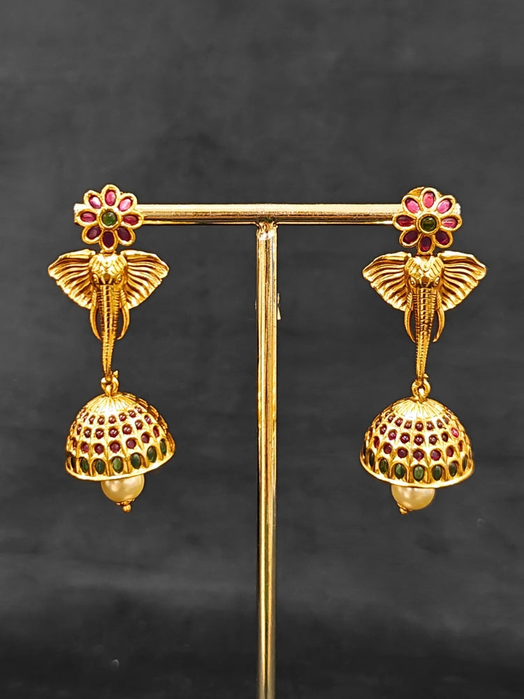 The Hastika Hasli Necklace Set featuring a traditional gold Collar hasli necklace and matching earrings with Goddess Ganesh in the middle, along with pink and green colored stones and golden elephants. Ideal party jewelry for any festive occasion. Festive Diwali look completed with a traditional temple necklace set.
