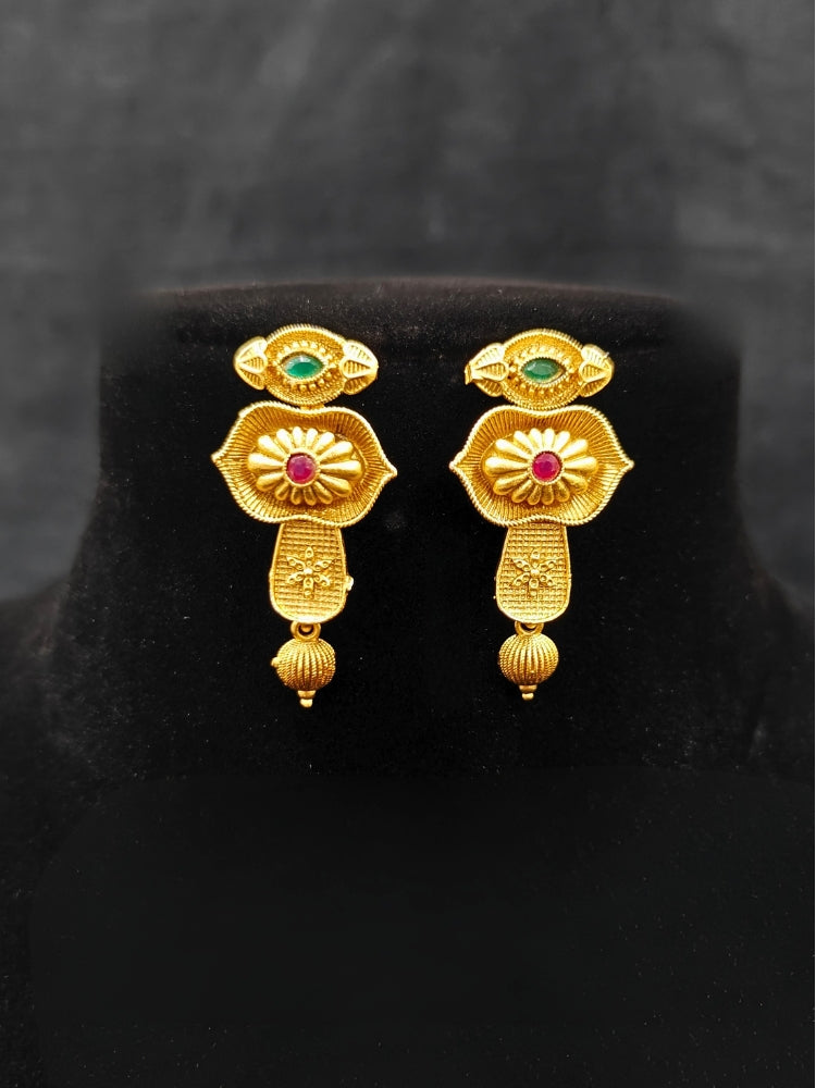 Close-up of an ornate traditional (Bright Gold Polish) Collar jewellery set and earrings with Pink and Green Colored Stone. Woman pairing a traditional Colored Stone necklace with a silk saree. Festive Diwali look enhanced with an imitation Colored Stone Necklace Set.