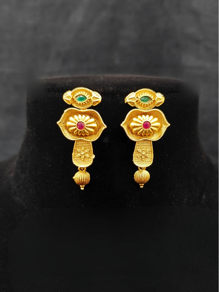 Close-up of an ornate traditional (Bright Gold Polish) Collar jewellery set and earrings with Pink and Green Colored Stone. Woman pairing a traditional Colored Stone necklace with a silk saree. Festive Diwali look enhanced with an imitation Colored Stone Necklace Set.