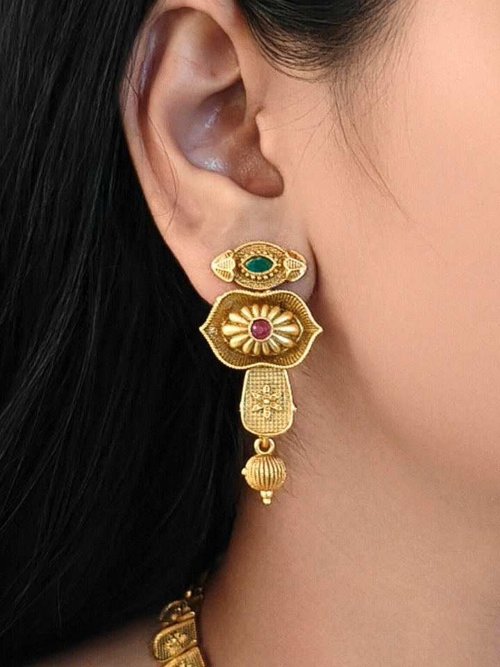 Close-up of a women wearing an ornate traditional (Bright Gold Polish) Collar jewellery set and earrings with Pink and Green Colored Stone. Woman pairing a traditional Colored Stone necklace with a silk saree. Festive Diwali look enhanced with an imitation Colored Stone Necklace Set.