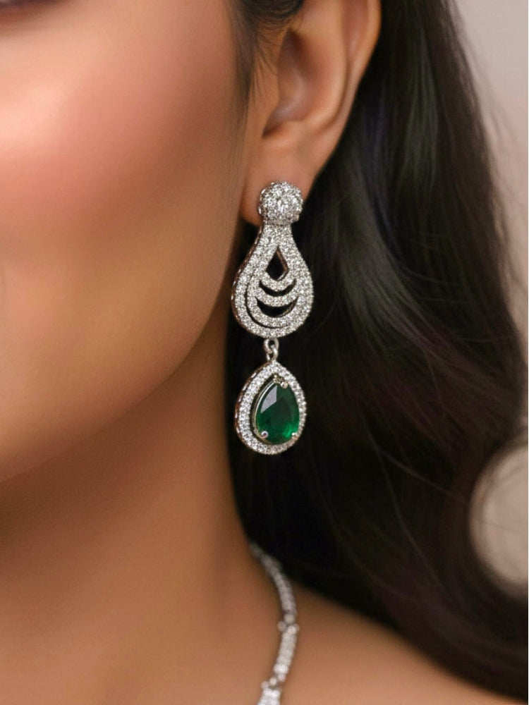 Close-up of a woman wearing an ornate Western Green Silver Polish Collar Diamond jewellery set and earrings and maangtikka with American Diamond and Colored Stones. Bride-to-be styled in a premium American diamond artificial necklace for her reception party. Woman styling a statement American diamond necklace with an off-shoulder gown for a reception.