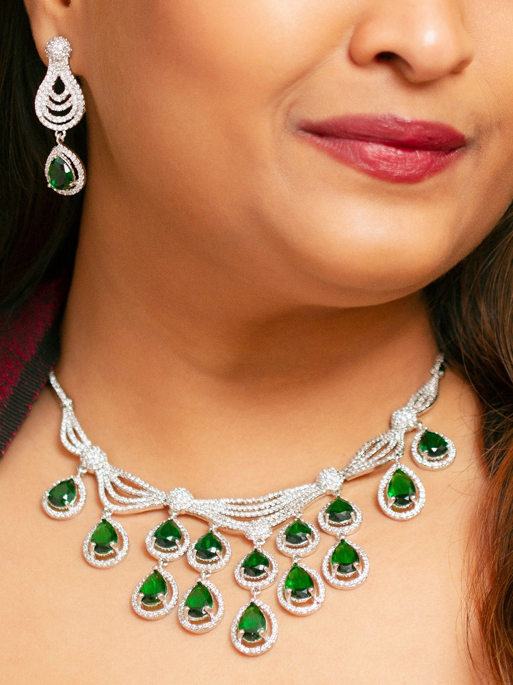 A woman showcasing a beautiful artificial diamond necklace with green colored stone and earrings and maangtikka set, ideal for festivals, family gatherings, and special celebrations in India. Perfect for bridal wear, weddings, and festive occasions.