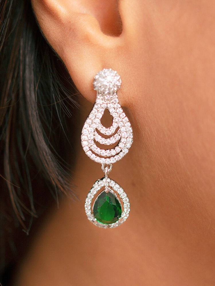 A stunning woman wearing a glamorous artificial diamond necklace with green colored stone paired with chic earrings and maangtika, perfect for bridal wear. This high-quality artificial diamond jewelry set is the ideal choice for modern brides looking for a budget-friendly option with timeless sparkle.