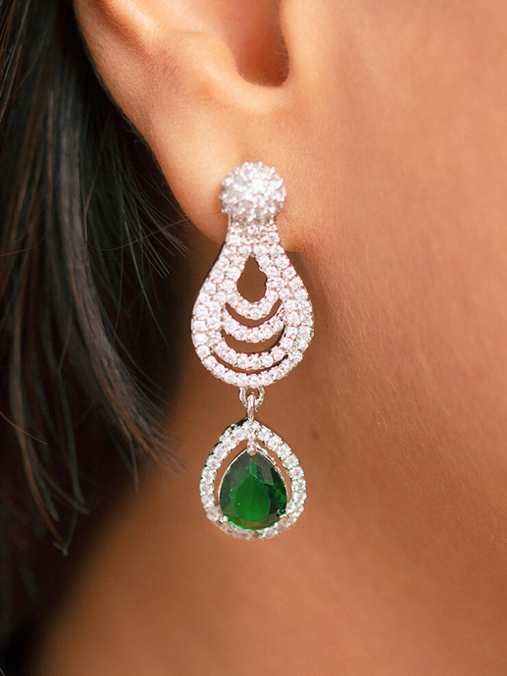 A stunning woman wearing a glamorous artificial diamond necklace with green colored stone paired with chic earrings and maangtika, perfect for bridal wear. This high-quality artificial diamond jewelry set is the ideal choice for modern brides looking for a budget-friendly option with timeless sparkle.