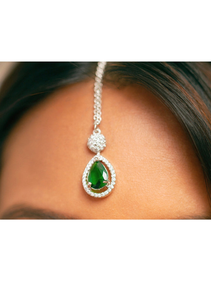 Close-up of a woman wearing a sparkling artificial diamond necklace with green colored stone and diamond earrings and maangtikka set, designed to offer a radiant, elegant look for any formal occasion or Indian wedding. This affordable diamond jewelry provides a flawless, luxurious alternative to natural diamonds.