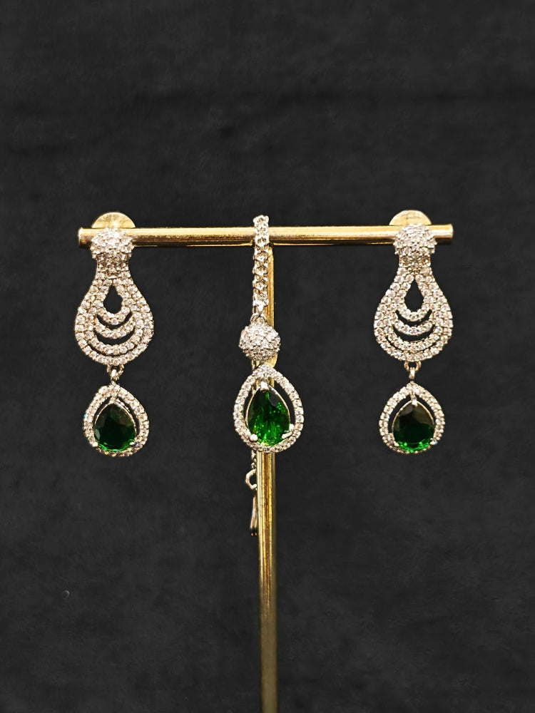 Close-up of an ornate Western Green Silver Polish Collar Diamond jewellery set and earrings and maangtikka with American Diamond and Colored Stones. A premium American diamond artificial necklace for reception party. A statement American diamond necklace with an off-shoulder gown for a reception.