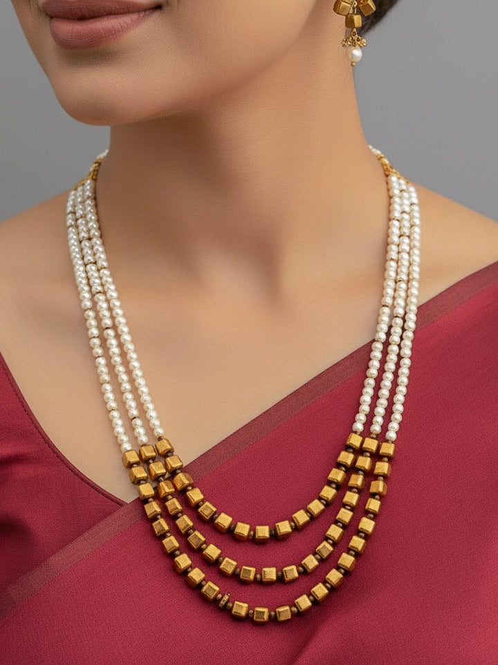 Close-up of a woman wearing an ornate Indo-Western White and Gold Pearl Layered Jewellery set and Earring with Pearls and American Diamond. Festive celebration look enhanced with traditional Pearl jewelry. Close-up of enamel work in Meenakari artificial Pearl jewelry.