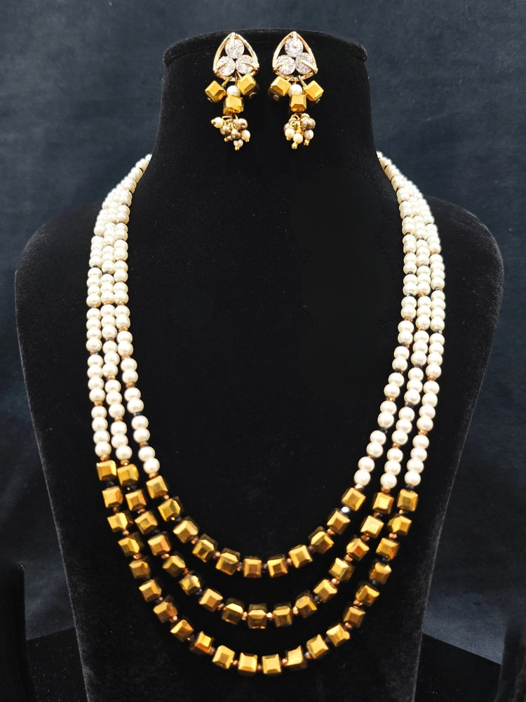 Close-up of an ornate Indo-Western White and Gold Pearl Layered Jewellery set and Earring with Pearls and American Diamond. Festive celebration look enhanced with traditional Pearl jewelry. Close-up of enamel work in Meenakari artificial Pearl jewelry.