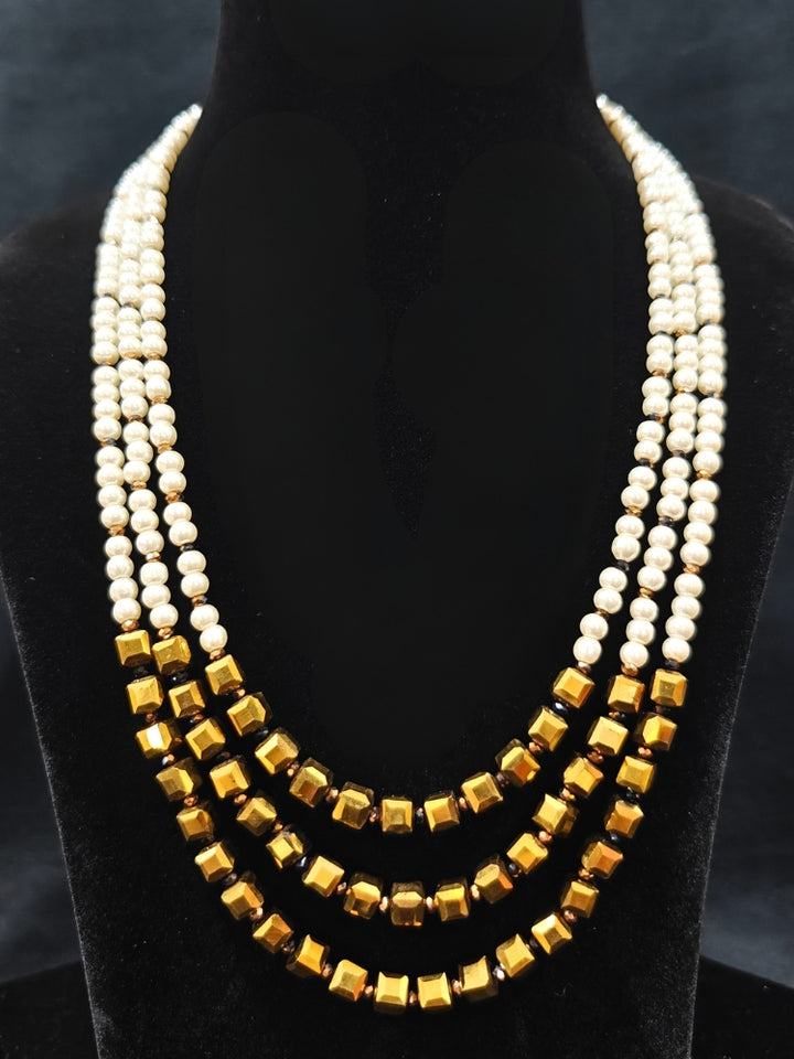Close-up of an ornate Indo-Western White and Gold Pearl Layered Jewellery set and Earring with Pearls and American Diamond. Festive celebration look enhanced with traditional Pearl jewelry. Close-up of enamel work in Meenakari artificial Pearl jewelry.