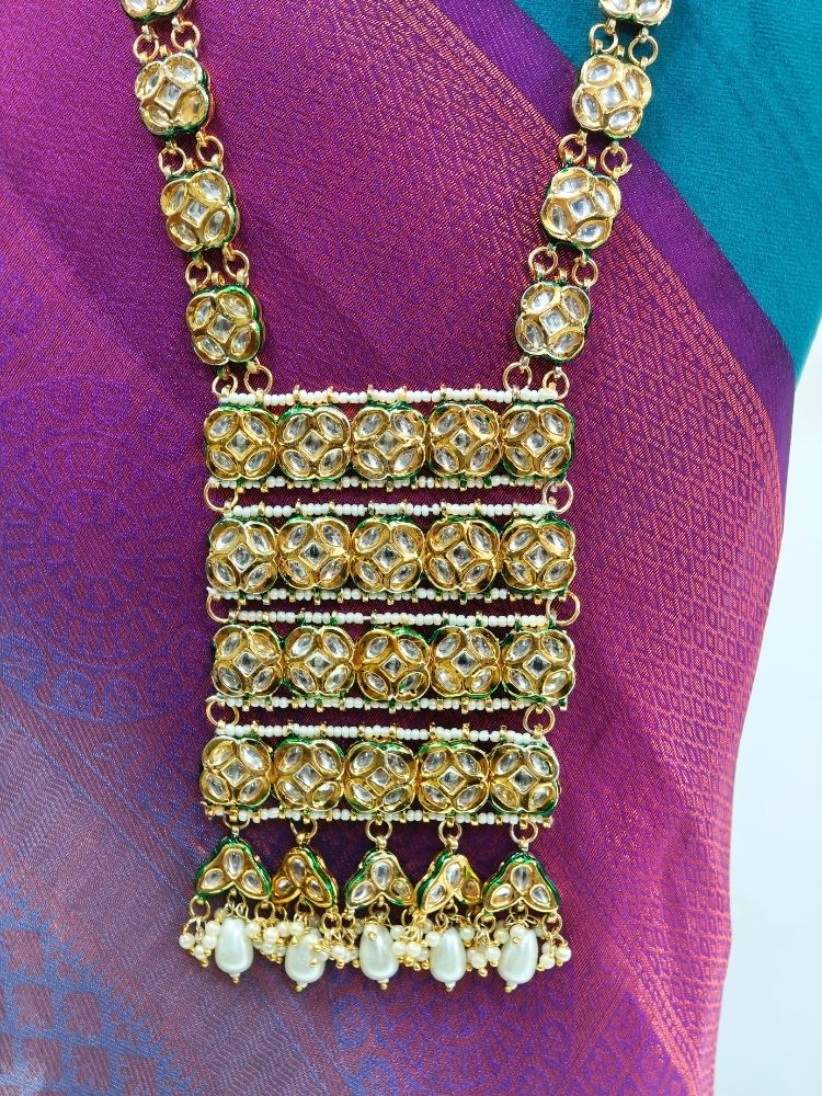 Close-up of an ornate traditional (Gold Polish) Long jewellery set and earrings with Kundan and Pearls. Festive saree styling with a premium artificial Kundan necklace. Mehendi ceremony look completed with a handcrafted Kundan jewelry set.