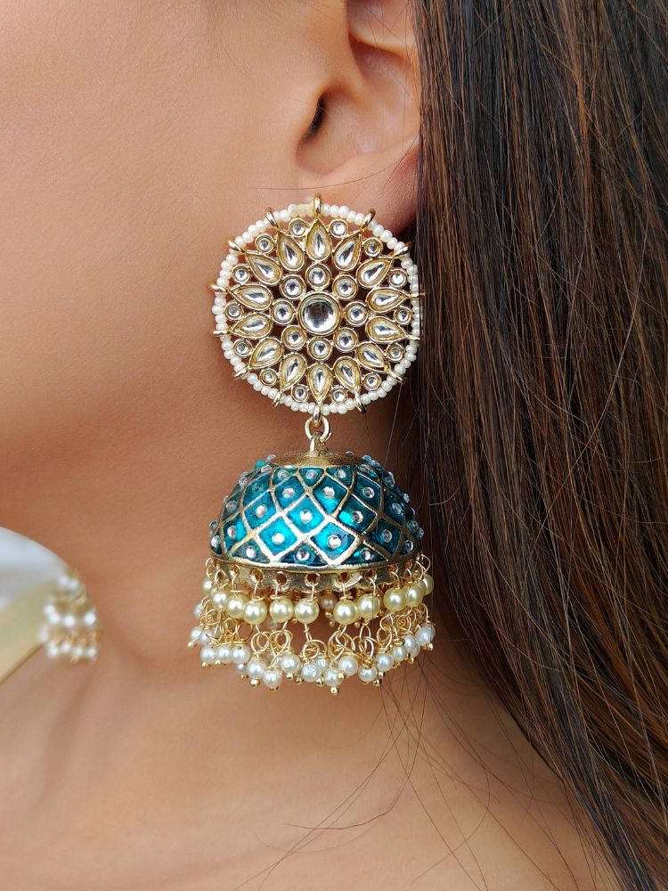 Close-up of a woman wearing an ornate traditional Teel Blue Meenakari gold Long Earrings with Pearls, Kundan and Meenakari. Wedding guest wearing a Meenakari artificial Earrings. Woman wearing trending Meenakari artificial Earrings for wedding season in India. 
