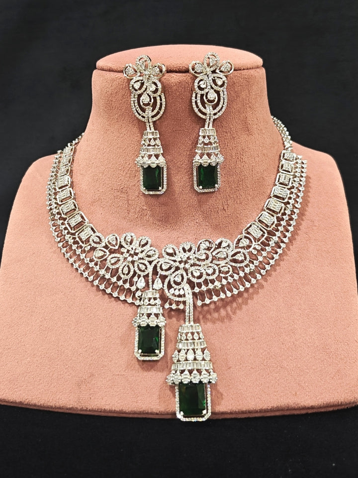 An exquisite artificial diamond necklace with green colored stone and matching earrings, designed for the perfect engagement look. This stunning artificial diamond jewelry set offers luxury and sophistication while being an affordable alternative to natural diamonds."