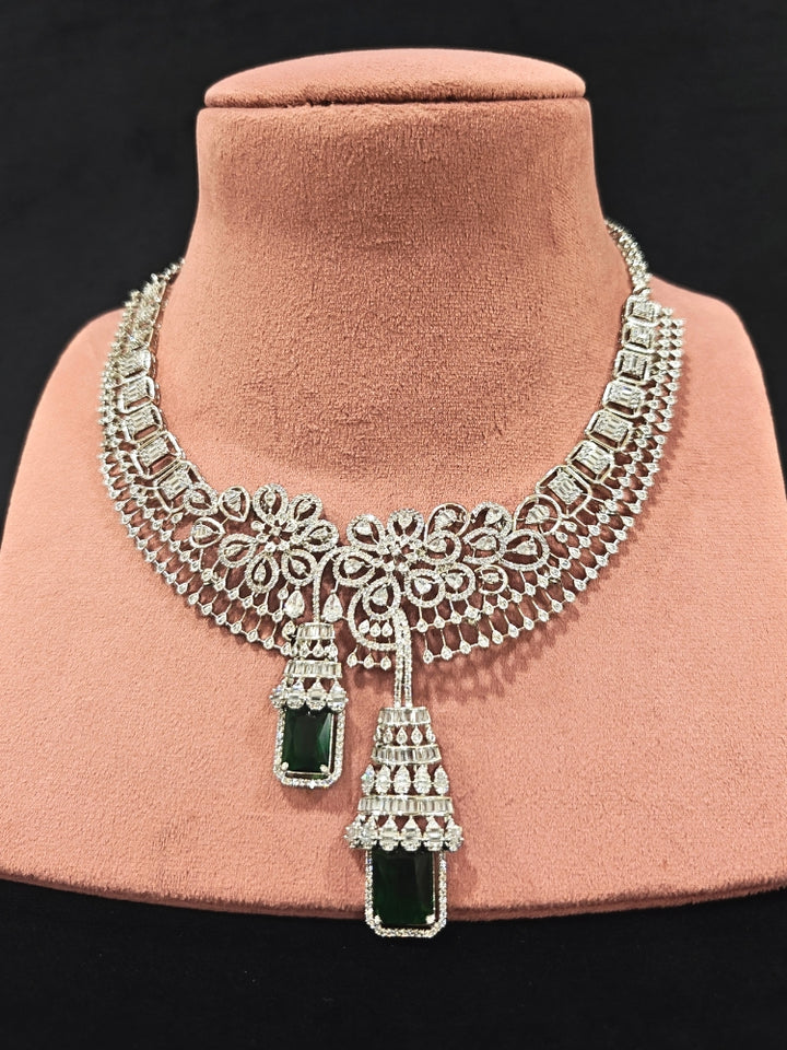 An exquisite artificial diamond necklace with green colored stone and matching earrings, designed for the perfect engagement look. This stunning artificial diamond jewelry set offers luxury and sophistication while being an affordable alternative to natural diamonds."