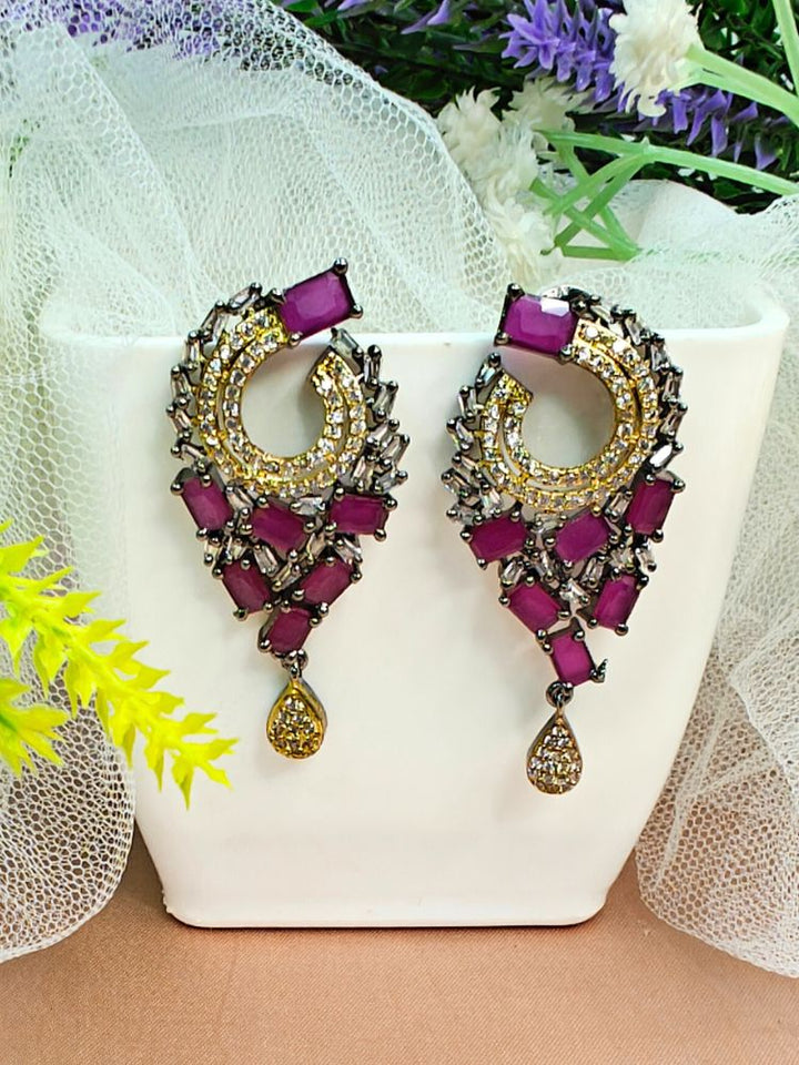 Close-up of an ornate Indo-Western (Black Polish Victorian Finish) Pink Earrings with American Diamond and Pink Colored Stones. Indo-western outfit styled with a statement Colored Stone Earrings set. Close-up shot of a high-quality Colored Stone artificial Earrings set worn for festive celebrations.