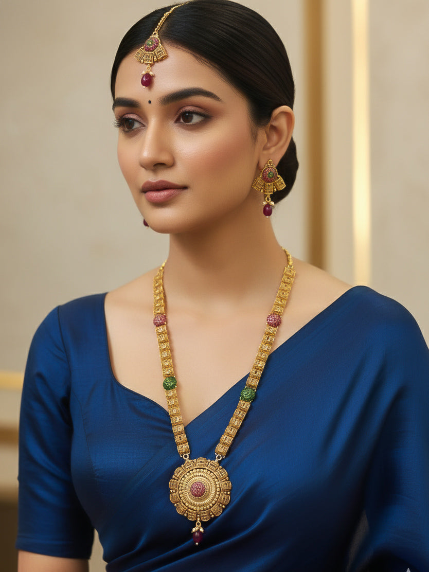 Close-up of a woman wearing an ornate traditional (Gold Polish) Long jewellery set and earrings and maangtikka with Colored Stones. Woman wearing lightweight artificial Colored Stone jewelry for long wedding functions. Saree look completed with elegant artificial Colored Stone jewelry for festive occasions.