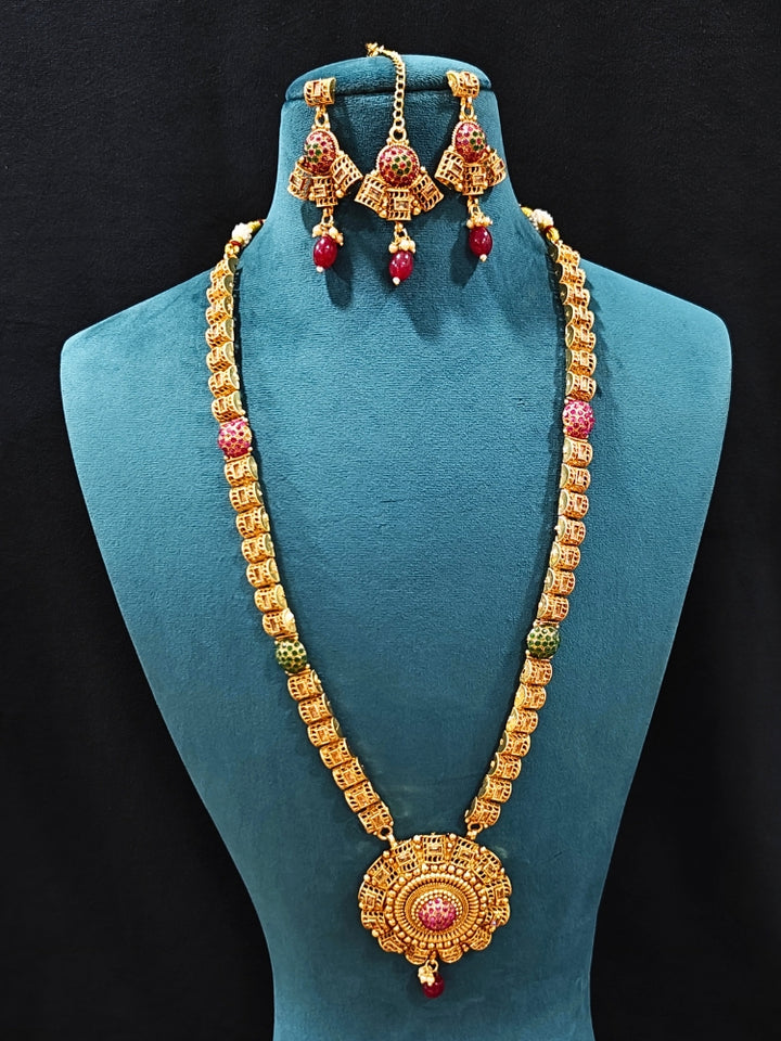Close-up of an ornate traditional (Gold Polish) Long jewellery set and earrings and maangtikka with Colored Stones. Woman wearing lightweight artificial Colored Stone jewelry for long wedding functions. Saree look completed with elegant artificial Colored Stone jewelry for festive occasions.