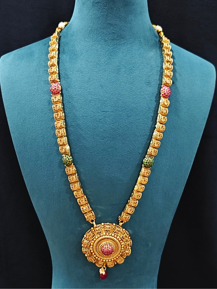 Close-up of an ornate traditional (Gold Polish) Long jewellery set and earrings and maangtikka with Colored Stones. Woman wearing lightweight artificial Colored Stone jewelry for long wedding functions. Saree look completed with elegant artificial Colored Stone jewelry for festive occasions.