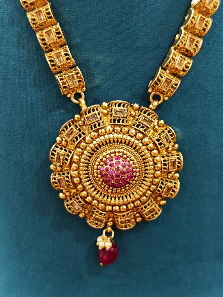 Close-up of an ornate traditional (Gold Polish) Long jewellery set and earrings and maangtikka with Colored Stones. Woman wearing lightweight artificial Colored Stone jewelry for long wedding functions. Saree look completed with elegant artificial Colored Stone jewelry for festive occasions.
