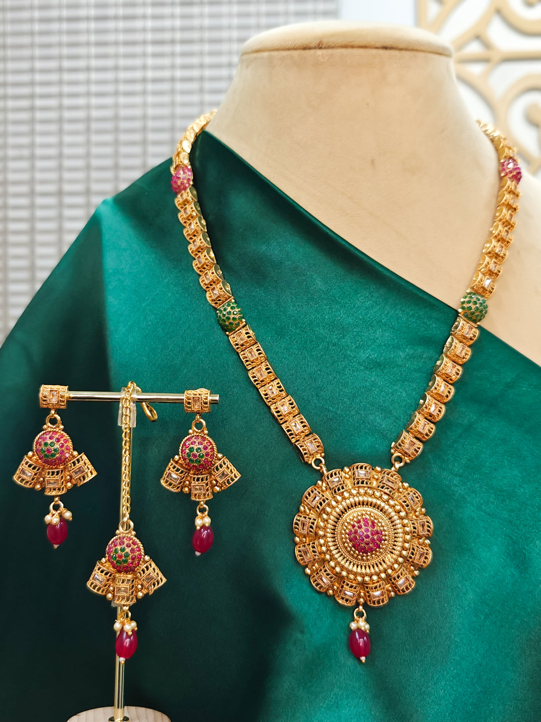 Close-up of an ornate traditional (Gold Polish) Long jewellery set and earrings and maangtikka with Colored Stones. Woman wearing lightweight artificial Colored Stone jewelry for long wedding functions. Saree look completed with elegant artificial Colored Stone jewelry for festive occasions.
