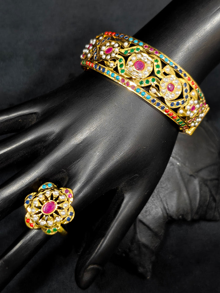 Close-up of an ornate traditional Navratan jadau gold Bracelet with matched Ring with pearls and Color Stone. A premium artificial Jadau bracelet with Ring for wedding celebrations. Close-up of a high-quality imitation Jadau bracelet with Ring for festive wear.