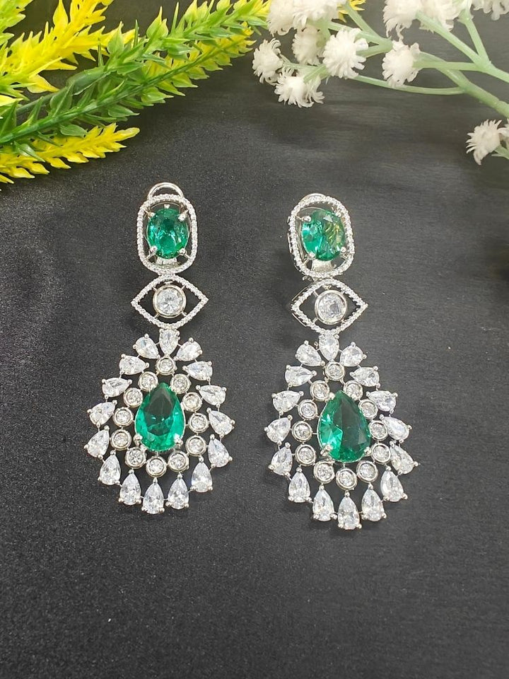 Ira Earrings—statement green brass earrings with American Diamonds and an intricate teardrop design. shown on a black background. 