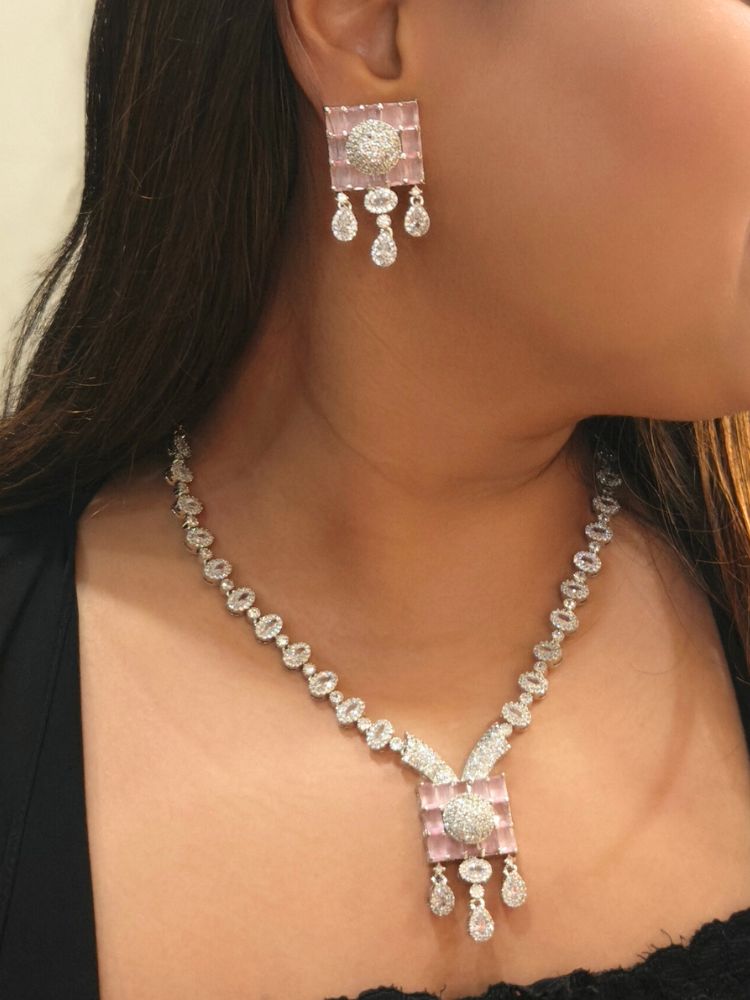 A woman wearing the Iris Mint Pink Necklace Set, adorned with mint pink stones, American diamonds, and teardrop dangles, perfectly paired with a black top.