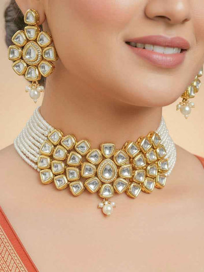 Close-up of a woman wearing an ornate traditional (Gold Polish) White Kundan  Choker jewellery set and earrings with Kundan and Pearls. Bride wearing a royal Kundan artificial necklace for wedding rituals. Close-up of detailed Kundan stones in artificial wedding jewelry. 