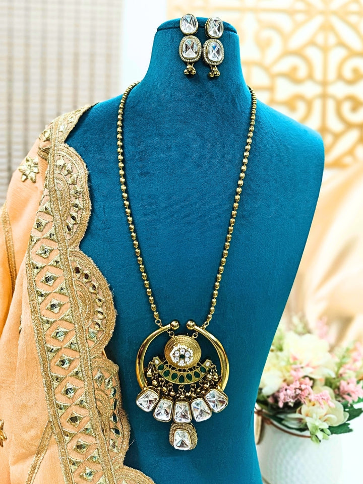 Make a bold style statement with this exquisite gold-tone statement necklace featuring a circular pendant adorned with emerald-green and crystal-white stones. Designed with intricate detailing and a regal finish, this necklace is perfect for weddings, festive occasions, and ethnic wear. Pair it with sarees, lehengas.