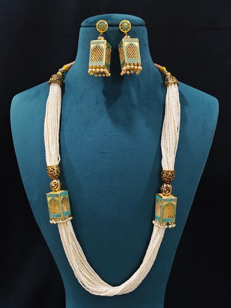 Close-up of an ornate traditional Mint Green Rajwadi gold Long jewellery set and earrings  with  Pearls and Meenakari. Festive Diwali outfit enhanced with a Rajwadi artificial necklace. Close-up of detailed Rajwadi craftsmanship in artificial jewelry. Close-up of enamel work in Meenakari artificial wedding jewelry.