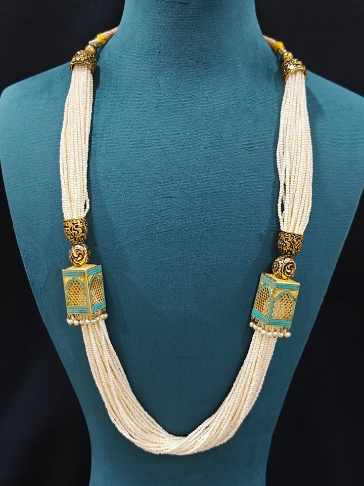 Close-up of an ornate traditional Mint Green Rajwadi gold Long jewellery set and earrings  with  Pearls and Meenakari. Festive Diwali outfit enhanced with a Rajwadi artificial necklace. Close-up of detailed Rajwadi craftsmanship in artificial jewelry. Close-up of enamel work in Meenakari artificial wedding jewelry.
